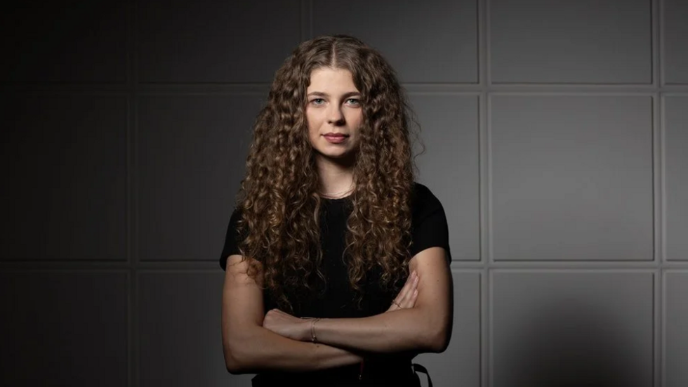 Studentka Uniwersytetu Łódzkiego stoi pewnie ze skrzyżowanymi rękami.