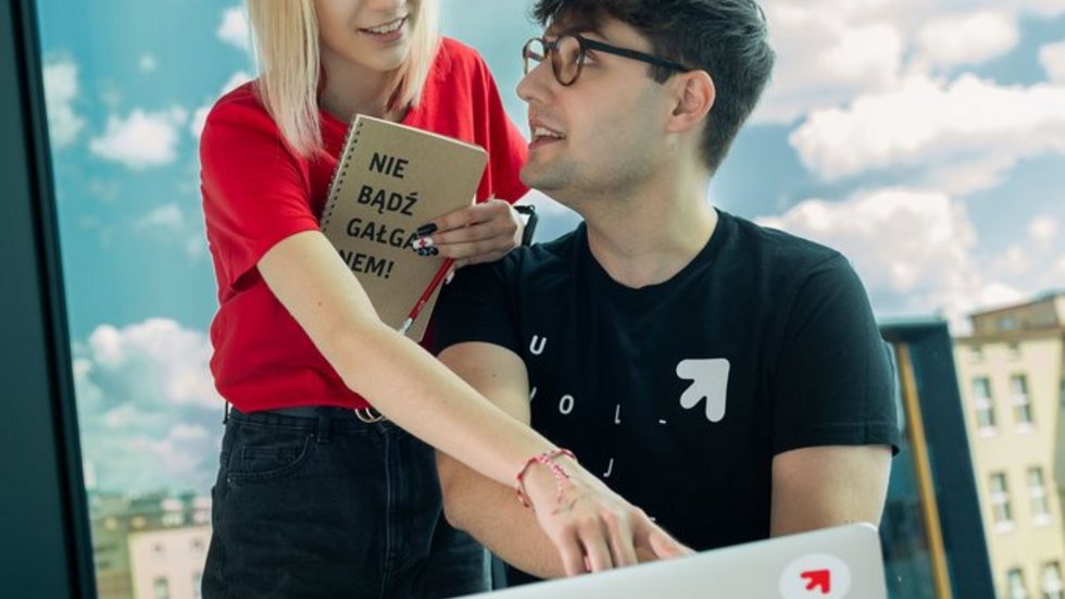 a girl and a boy sitting at a laptop