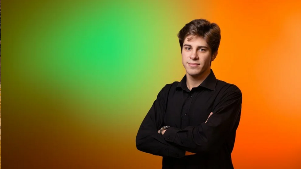 Student Uniwersytetu Łódzkiego stoi pewnie i uśmiecha się do kamery.