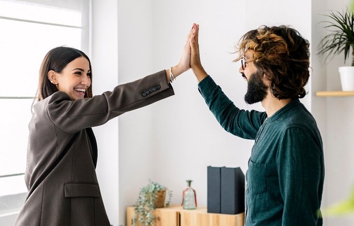 A smiling woman giving high-five to her happy friend