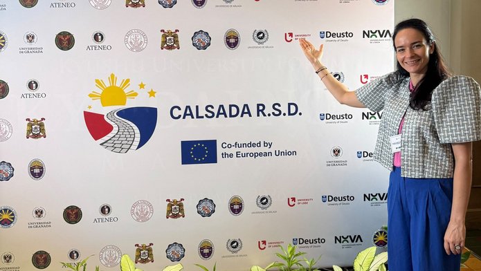 a woman standing in front of a backdrop displaying institutional logos