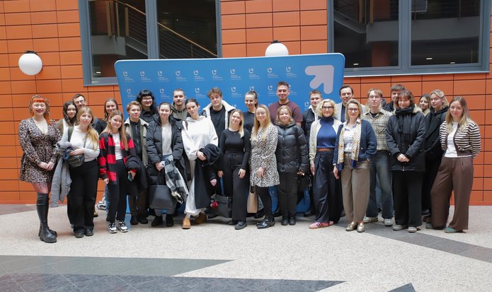 A group of people in front of the banner of the Faculty of Management of the University of Lodz
