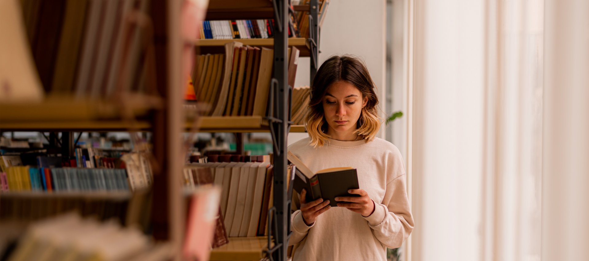 dziewczyna czytająca książkę w bibliotece