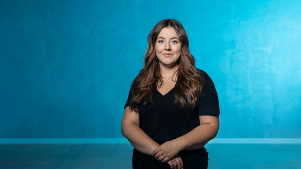 Studentka Uniwersytetu Łódzkiego uśmiecha się do kamery.